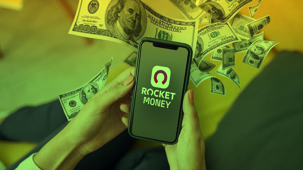 Holding a iphone with Rocket Money App on screen, money spreading out