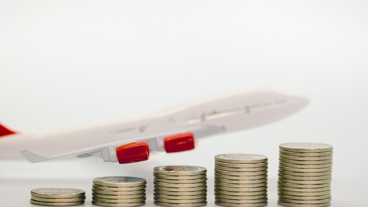 Closeup of stack of silver coins as bar chart and airplane model on white table