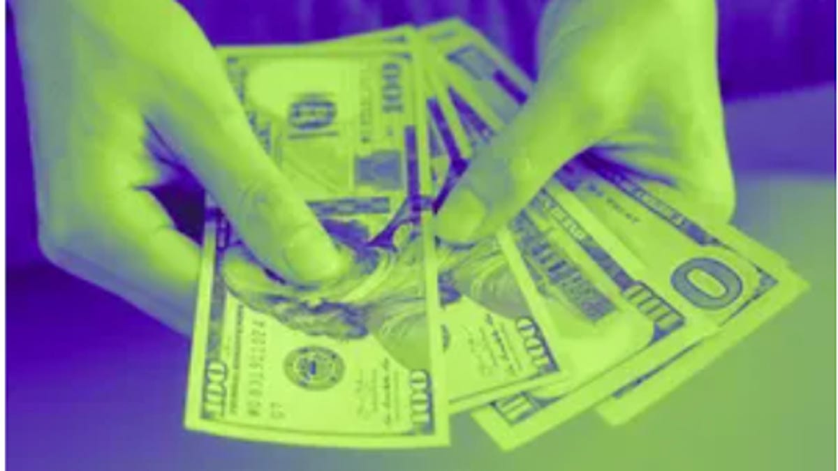 Someone holds fanned-out one hundred dollar bills.